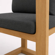 Detalle de silla de madera con tapizado negro y acabado natural